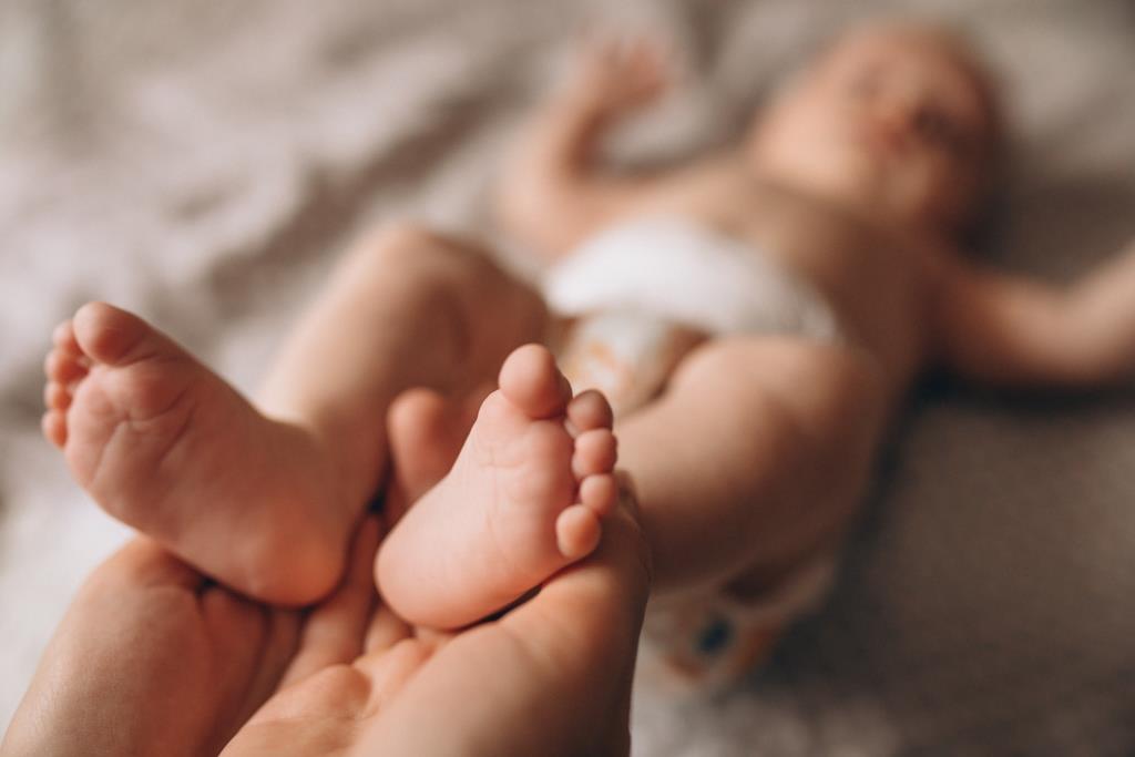 Mother holding newborn baby feet